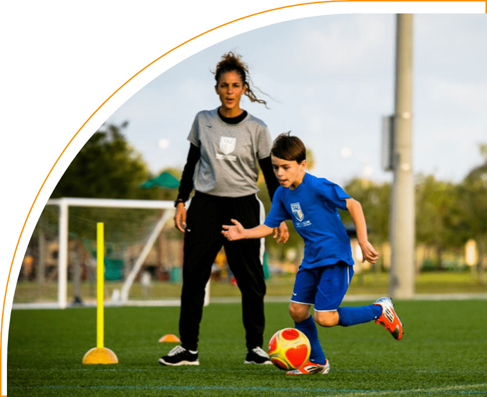 A woman and boy playing soccer on the field.