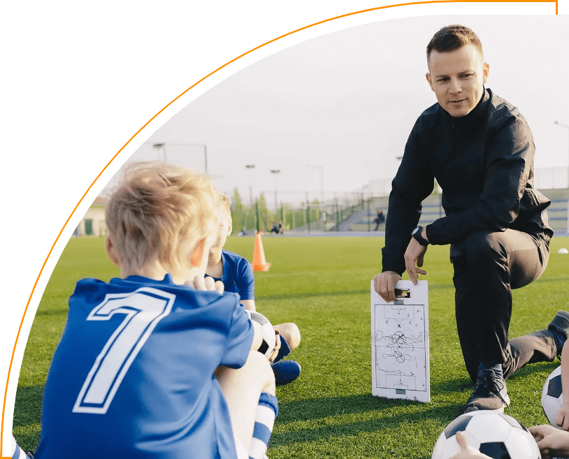 A man is teaching a boy how to play soccer.