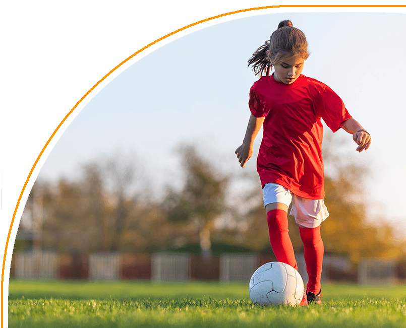 A young girl kicking around a soccer ball.