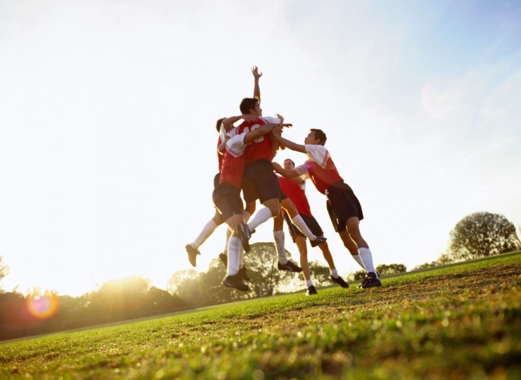 A group of people jumping in the air to catch a soccer ball.